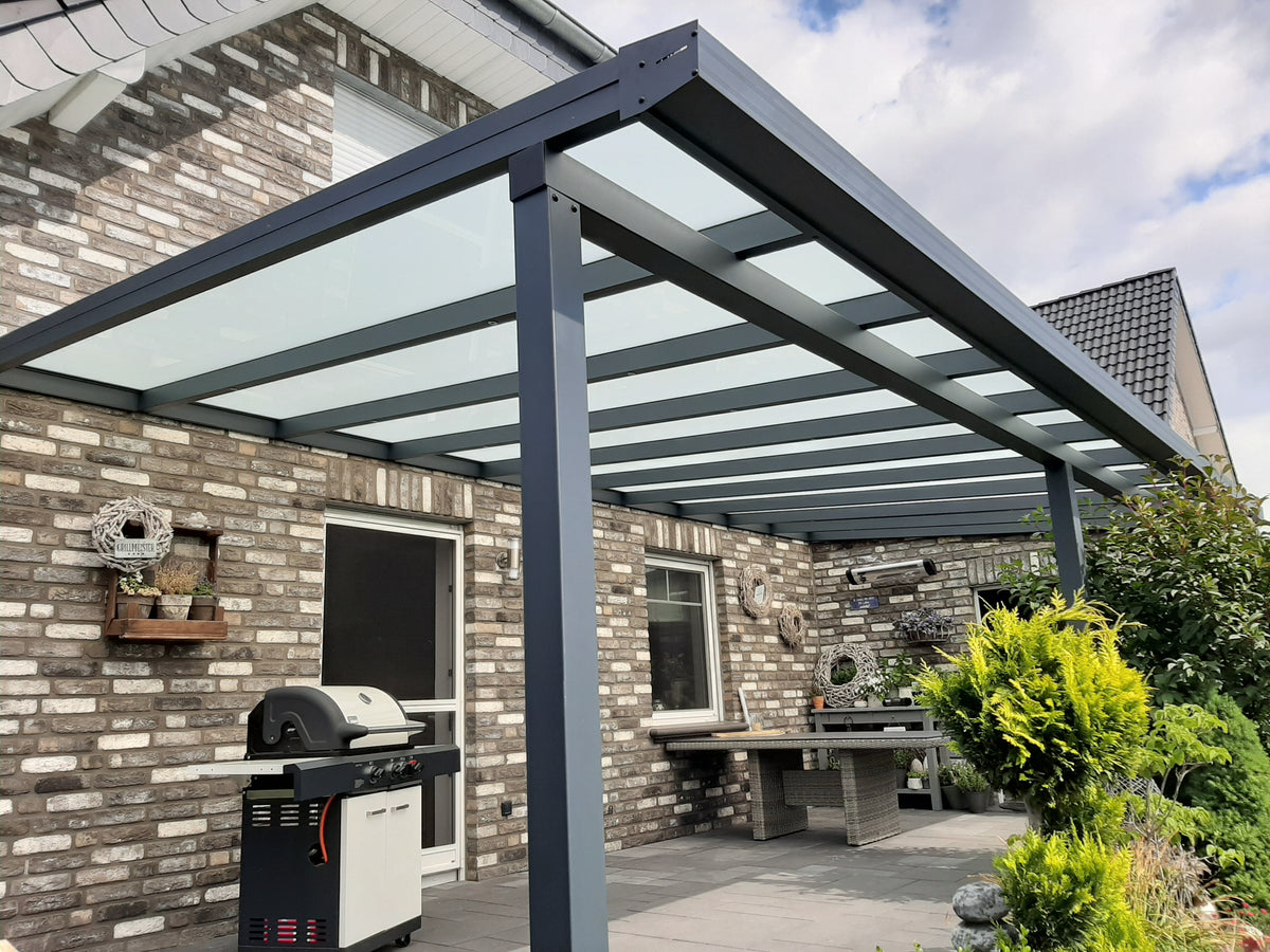 Terrassenüberdachung aus Aluminium in Anthrazit mit lichtdurchlässiger Eindeckung an einer Natursteinfassade