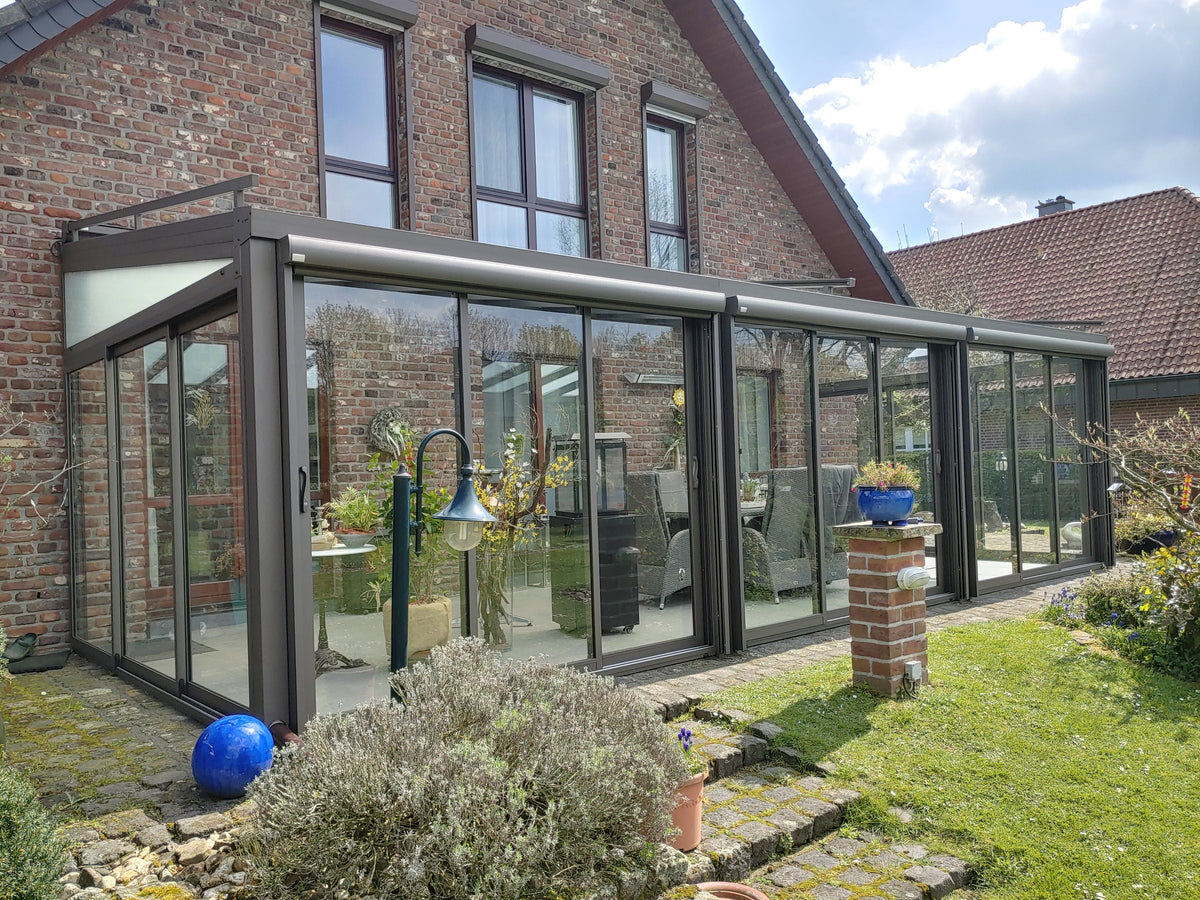 Glasschiebewand mit Aluminiumrahmen in Anthrazit im Kaltwintergarten, Blick auf Klinkerwand und Pflanzen