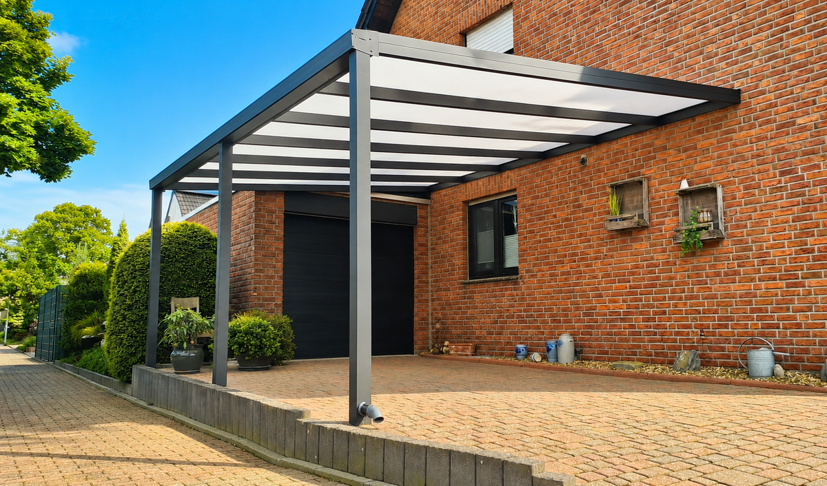 Carport aus Aluminium in Anthrazit vor einem Klinkerhaus mit Garagentor und Hecke